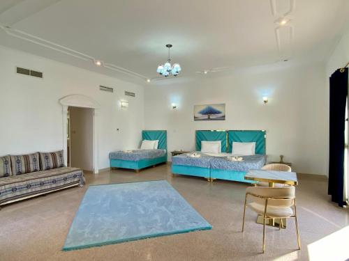 a room with two beds and a table and chairs at Arabian Nights Nook in Muscat