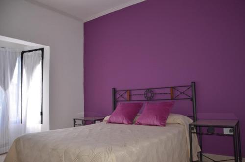 a bedroom with purple walls and a bed with two pink pillows at Cabañas San Lorenzo in San Lorenzo