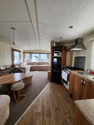 a kitchen and living room with a stove and a table at Peaceful Seaside Getaway in Mainsriddle