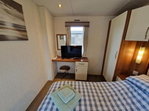 a bedroom with a bed and a desk with a television at Peaceful Seaside Getaway in Mainsriddle