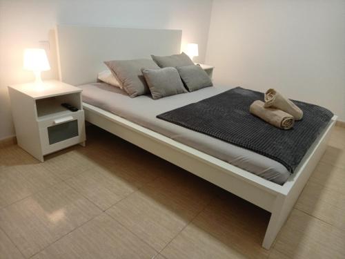 1 dormitorio con 1 cama blanca y mesita de noche en La Casita de Alaia, en Vecindario