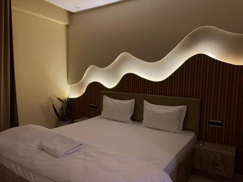 a bedroom with a large white bed with a light above it at Omaxe Hazratganj- Healing Staytion- Lucknow in Lucknow