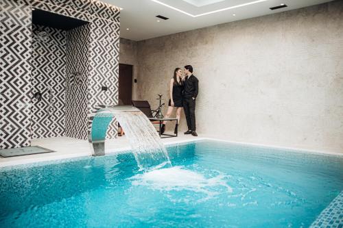 a man and a woman standing next to a swimming pool at Motel Delphin in Pristina