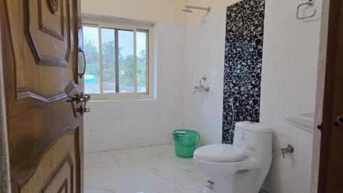 ein Badezimmer mit Toilette und Fenster in der Unterkunft VilleFortune 3BHK Cottage In Nainital in Bhīm Tāl