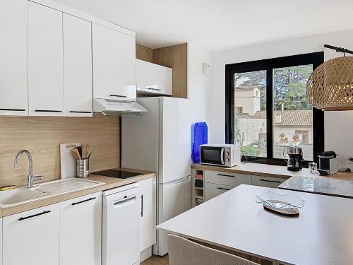 une cuisine avec des placards blancs et un comptoir blanc dans l'établissement bel appartement deux pas des plages 351L, à Cannes