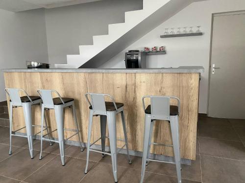 une cuisine avec quatre tabourets blancs à un comptoir dans l'établissement Les Chambres avec SDB,1 Studio l'intérieur complètement rénové en 2024,plage du Débarquement 5 minutes à pied, à Vierville-sur-Mer