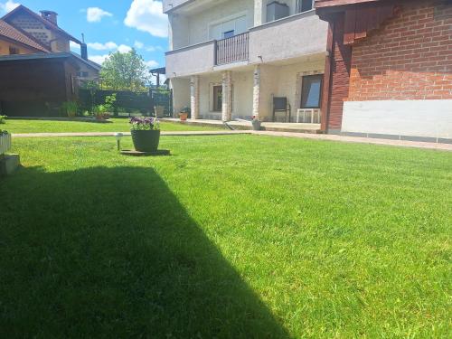 a green yard with a pot of flowers in the yard at Studio Spa Sweet Nest jacuzzi-sauna-bazen in Otočac
