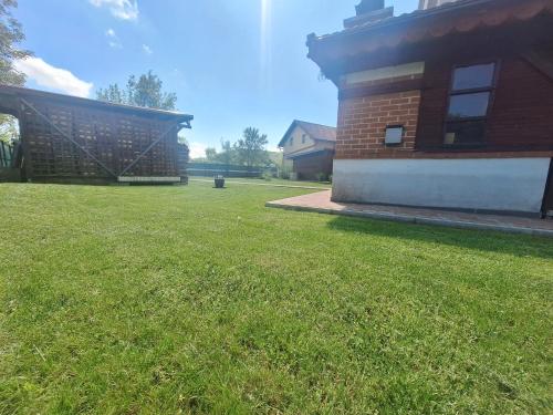 a yard next to a brick building with a grass field at Studio Spa Sweet Nest jacuzzi-sauna-bazen in Otočac