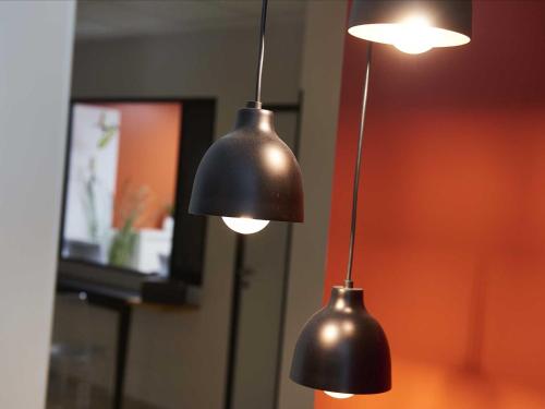 two black lights hanging from a wall at L'aparthoteL LhL in Dijon