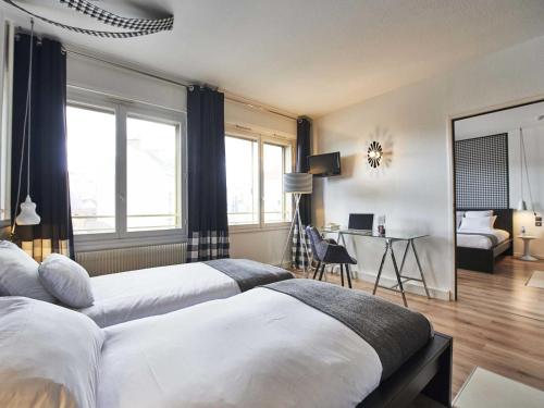 a bedroom with two beds and a desk with a laptop at L'aparthoteL LhL in Dijon