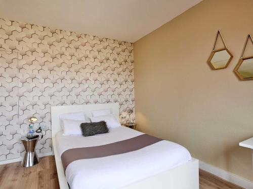 a bedroom with a white bed and a wall at L'aparthoteL LhL in Dijon