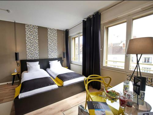 a hotel room with two beds and a desk with a table sidx sidx at L'aparthoteL LhL in Dijon