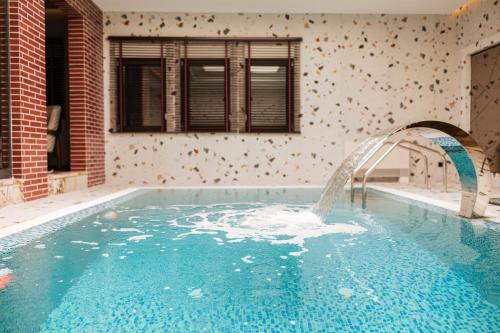 a large swimming pool with a water fountain at Motel Delphin in Pristina