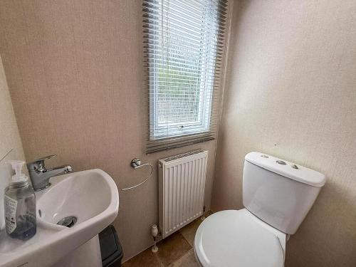 ローストフトにある6 Berth Luxury Caravan With Full Sea Views At Azure Seas In Suffolk Ref 32069Azの白いトイレと洗面台のあるバスルーム