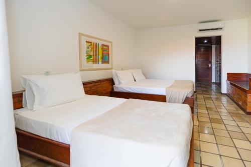 two beds in a room with white sheets at Mirai Beach Hotel in Natal