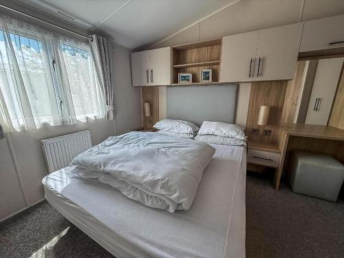 a bedroom with a white bed and a desk at Beautiful 6 Berth Caravan, Nearby Beach In Suffolk Ref 68016Bs in Lowestoft