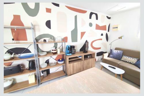 un salon avec un canapé et un mur avec une abstraction dans l'établissement Cap sur La Flotte ,Maisons centre-ville Jardin mélange art fleurs, à La Flotte