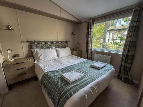 a bedroom with a bed with two towels on it at Beautiful Lodge With Decking At Azure Seas In Suffolk, Sleeps 6 Ref 32217Og in Lowestoft