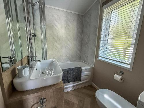 a bathroom with a sink and a toilet and a tub at Beautiful Lodge With Decking At Azure Seas In Suffolk, Sleeps 6 Ref 32217Og in Lowestoft