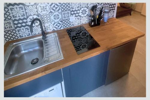 une cuisine avec un évier et un plan de travail en bois dans l'établissement Cap sur La Flotte ,Maisons centre-ville Jardin mélange art fleurs, à La Flotte
