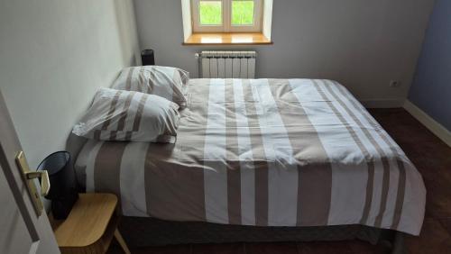a bed with a striped comforter in a bedroom at L'Orée de Tronçais in Le Plaix