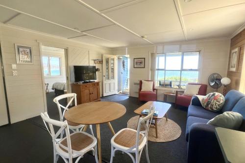 a living room with a blue couch and a table at BINALONG BEACH COTTAGE Beachfront at Bay of Fires Next to Restaurant in Binalong Bay