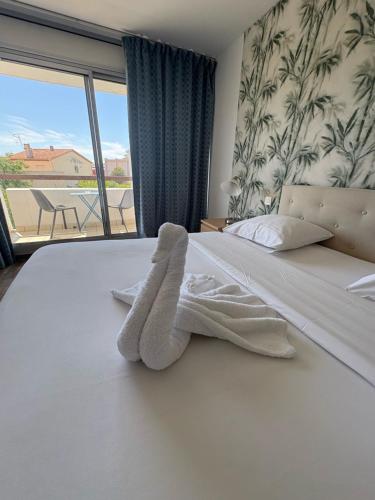 a bedroom with a white bed with a large window at Hotel Sable Et Soleil - Port, Plage & Jacuzzi privé in Fréjus