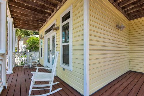 a yellow house with a rocking chair on a porch at Brzee Bungalow in Destin