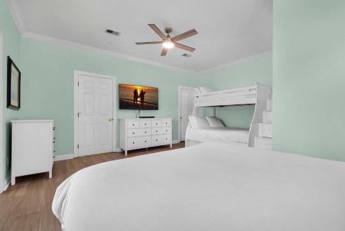 a white bedroom with a bed and a tv at Brzee Bungalow in Destin