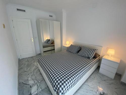 a bedroom with a bed with black and white checkered pillows at Apartamento moderno en el centro de Huelva in Huelva