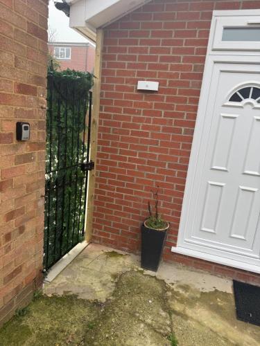 a white door with a potted plant next to a brick building at Modern Studio Luxe Heathrow London in New Bedfont