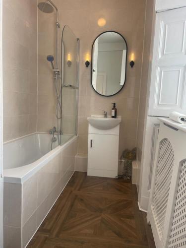 a bathroom with a tub and a sink and a mirror at Stunning seafront apartment in Brighton & Hove
