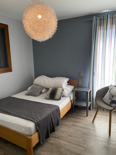a bedroom with a bed and a chair and a chandelier at Le petit Repaire de Sailhan, Ecolodges in Sailhan