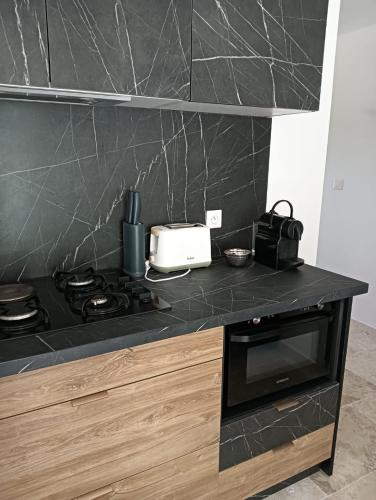 - une cuisine avec un comptoir noir et une cuisinière dans l'établissement Domaine Bastide Blanche, à Gréoux-les-Bains