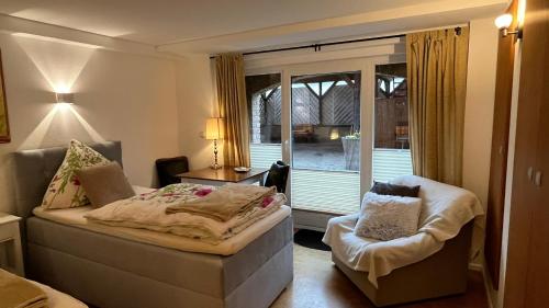 a bedroom with a bed and a chair and a window at Ferienwohnung am Sonnenstein in Brehme