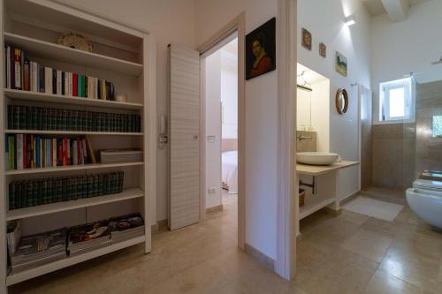 a bathroom with a toilet and a book shelf with books at Isola Country House - Villa by the beach in Plemmirio