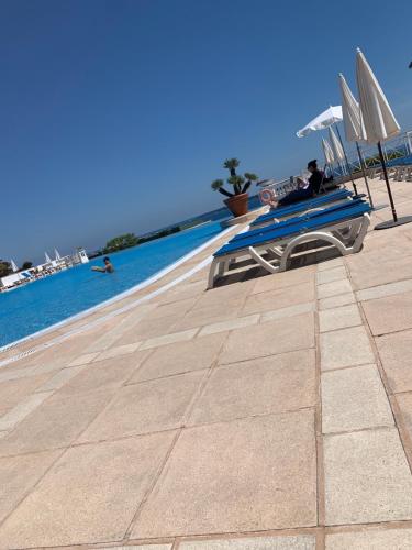 une piscine avec des chaises et des parasols au bord de l'eau dans l'établissement Villa Francia Résidence piscine tennis à 500m des plages de Cannes, à Cannes