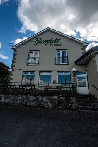 a building with a sign on the side of it at Greenfield Lodge Hotel Bar & Bistro in Headford