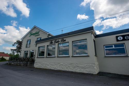 a white building with a sign on the side of it at Greenfield Lodge Hotel Bar & Bistro in Headford