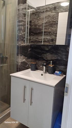 a bathroom with a white sink and a shower at Perla Beach Apartments in Ofrínion