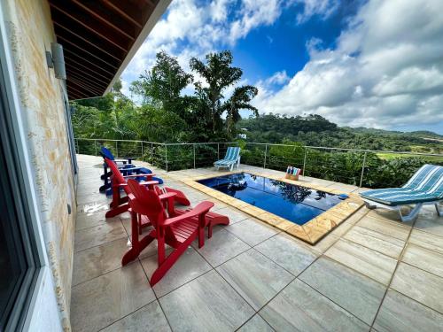 a patio with red chairs and a swimming pool at Spectacular Luxury Rental With Ocean Views And Private Pool in Roatan