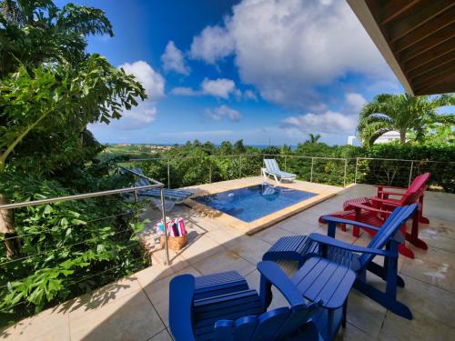 a patio with blue and red chairs and a swimming pool at Spectacular Luxury Rental With Ocean Views And Private Pool in Roatan