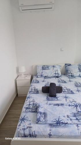 a bedroom with a bed with a blue and white comforter at Perla Beach Apartments in Ofrínion