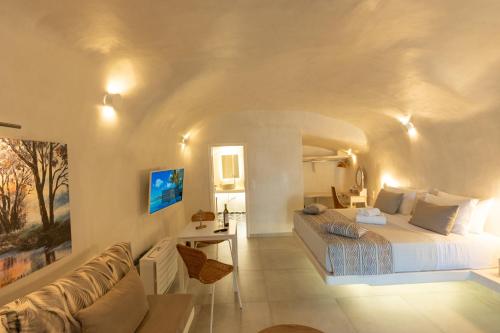 a white bedroom with a bed and a couch at Rody Caves in Oia