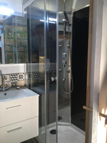 une douche avec une porte vitrée dans une salle de bain dans l'établissement La Campagne à la Mer, proche d'Etretat, à Angerville-la-Martel