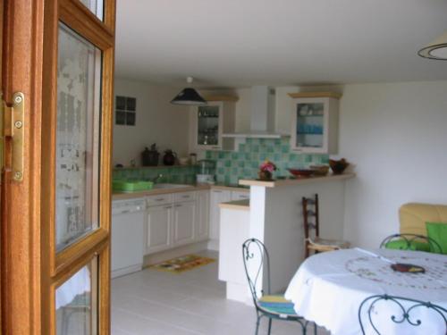 une cuisine avec une table et des chaises dans une pièce dans l'établissement Gîte Les Places avec piscine, à La Celle-sous-Gouzon