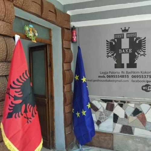 two flags in front of a building with a sign at Guest House Bake in Gjirokastër