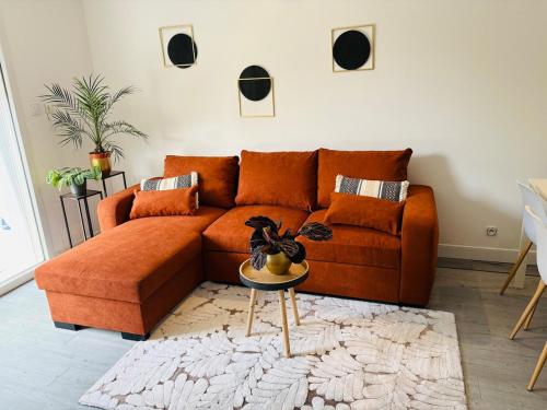 - un canapé orange dans le salon avec une table dans l'établissement Appartement cosy, terrasse privée, parking, centre ville, à Mont-de-Marsan