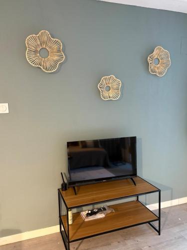 un salon avec une télévision et deux horloges au mur dans l'établissement Appartement cosy, terrasse privée, parking, centre ville, à Mont-de-Marsan