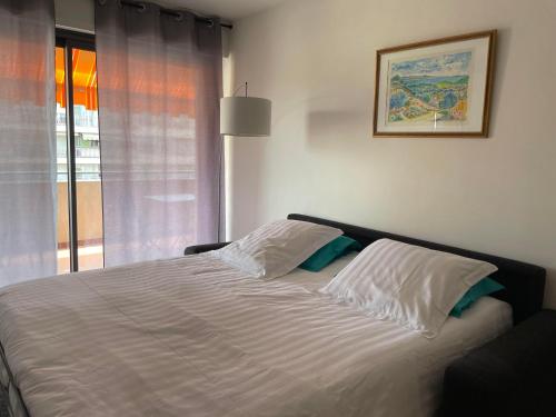 une chambre avec un grand lit blanc avec une fenêtre dans l'établissement Le Suquetan, à Cannes